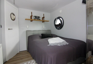 Bedroom on Houseboat «Lina» in Germany, featuring a round porthole window, bed and modern decor.