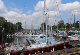 Photo of sailboats moored at a marina, including the 'VAGABOND', under a partly cloudy sky in Germany.