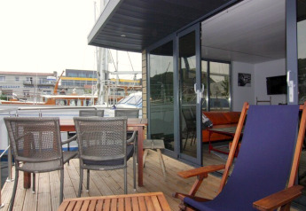 Terras van houseboat «Lina» in Duitsland met buitenzitjes, tafel en uitzicht op de jachthaven.
