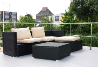 Outdoor seating area on Houseboat Lina in Germany with black wicker furniture and beige cushions on deck.