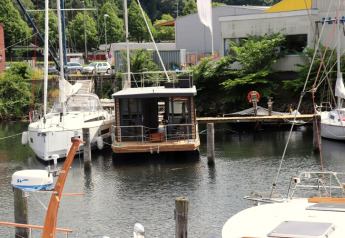 Houseboat «Lina» afgemeerd aan een steiger in Duitsland, omringd door zeilboten en zomers groen.