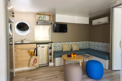 Intérieur moderne d'un lodge à Tamarit Park Resort, Espagne, avec cuisine, canapé, table basse et poufs.