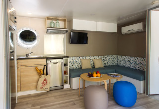 Intérieur moderne d'un lodge à Tamarit Park Resort, Espagne, avec cuisine, canapé, table basse et poufs.