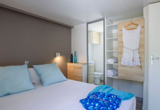 Chambre au Tamarit Park Resort 2 PATIO en Espagne avec lit double, coussins bleus et armoire ouverte.