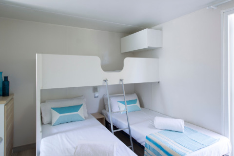 Chambre moderne au Tamarit Park Resort 2 PATIO en Espagne avec deux lits simples, un lit superposé et déco épurée.