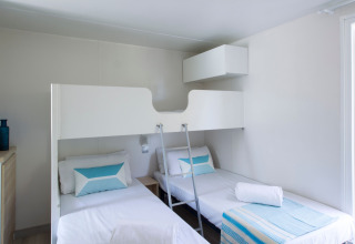 Chambre moderne au Tamarit Park Resort 2 PATIO en Espagne avec deux lits simples, un lit superposé et déco épurée.