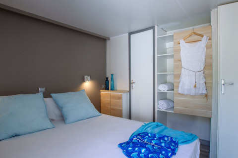 Chambre moderne au Tamarit Park Resort 2 PATIO en Espagne avec lit double, coussins bleus et armoire ouverte.