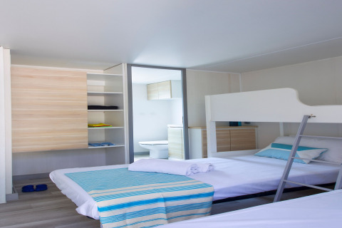 Chambre lumineuse au Tamarit Park Resort 2 PATIO en Espagne avec lits superposés, étagère et salle de bain.