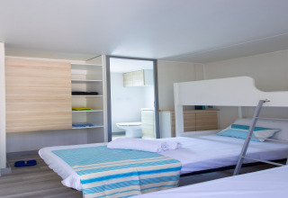 Chambre lumineuse au Tamarit Park Resort 2 PATIO en Espagne avec lits superposés, étagère et salle de bain.