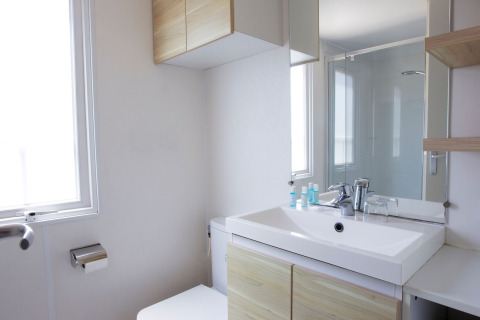 Salle de bain moderne au Tamarit Park Resort 2 PATIO en Espagne avec lavabo, miroir, toilettes et fenêtre.