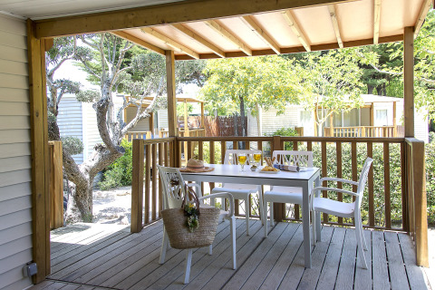 Terrasse couverte en bois avec table et chaises blanches, dressée pour un repas au Tamarit Park Resort Espagne.