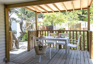 Terrasse couverte en bois avec table et chaises blanches, dressée pour un repas au Tamarit Park Resort Espagne.