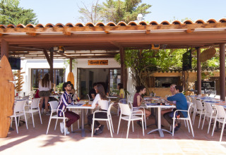 Terrasse du Tamarit Park Resort 2 PATIO en Espagne, clients assis sous un auvent en bois profitant du repas.