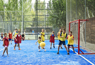 Des enfants jouent à un jeu de balle sur un terrain bleu avec des chasubles colorées à Tamarit Park Resort 2 PATIO, Espagne.