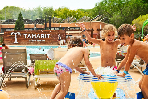 Des enfants jouent près d’une fontaine d’eau à la piscine du Tamarit Park Resort 2 PATIO, Espagne, lors d’une journée ensoleillée.