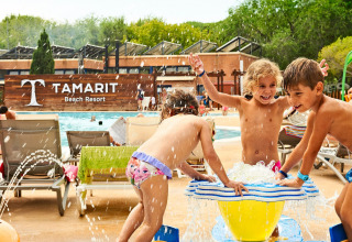 Des enfants jouent près d’une fontaine d’eau à la piscine du Tamarit Park Resort 2 PATIO, Espagne, lors d’une journée ensoleillée.