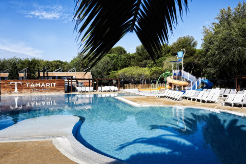 Piscine extérieure et toboggan aquatique au Tamarit Park Resort 2 PATIO en Espagne, avec transats et verdure.