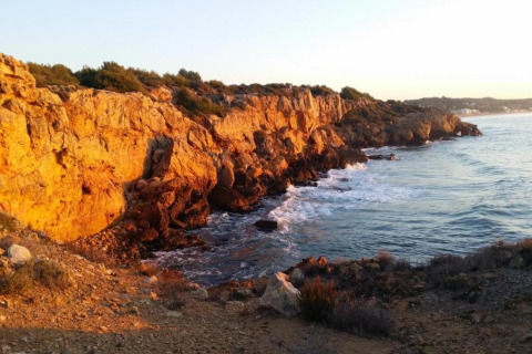 Falaises dorées au coucher du soleil près de Tamarit Park Resort en Espagne, surplombant une mer agitée.
