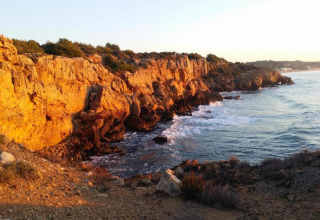 Falaises dorées au coucher du soleil près de Tamarit Park Resort en Espagne, surplombant une mer agitée.