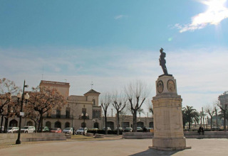 Place ensoleillée avec statue et arbres près du Tamarit Park Resort 2 PATIO en Espagne, ambiance paisible.