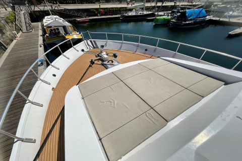 View of the houseboat Yacht Aquamarina’s deck at the dock, showing seating area and surrounding boats.