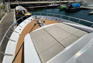 View of the houseboat Yacht Aquamarina’s deck at the dock, showing seating area and surrounding boats.