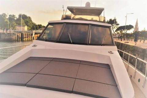 Front deck of houseboat Yacht Aquamarina docked by the pier during sunset, with cushions and windows.