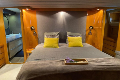 Modern bedroom on houseboat Yacht Aquamarina with double bed, wood paneling, and en-suite bathroom.