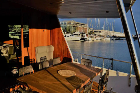 View from Yacht Aquamarina houseboat, sunlit dining area with marina and boats in the background.