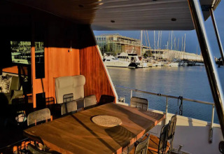 View from Yacht Aquamarina houseboat, sunlit dining area with marina and boats in the background.