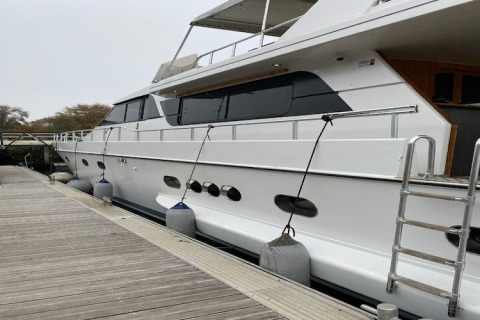 Houseboat named Yacht aquamarina docked at wooden pier, side view with fenders along the hull.