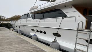 Houseboat named Yacht aquamarina docked at wooden pier, side view with fenders along the hull.