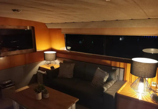 Stylish lounge area on houseboat Yacht Aquamarina with sofa, table lamps and large night window view.