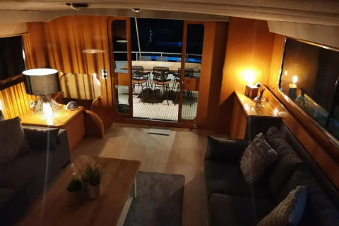 Cozy living area inside Yacht Aquamarina houseboat with stylish lighting and terrace view at night.