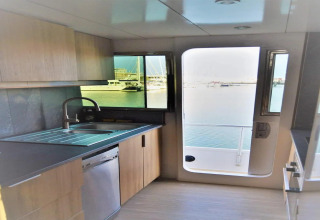 Modern kitchen inside houseboat Yacht Aquamarina with harbor view through window and open door.