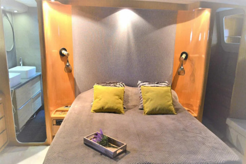 Bedroom on the Yacht Aquamarina houseboat with double bed, yellow cushions and a modern bathroom.
