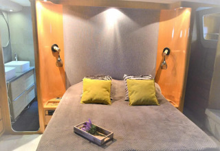 Bedroom on the Yacht Aquamarina houseboat with double bed, yellow cushions and a modern bathroom.