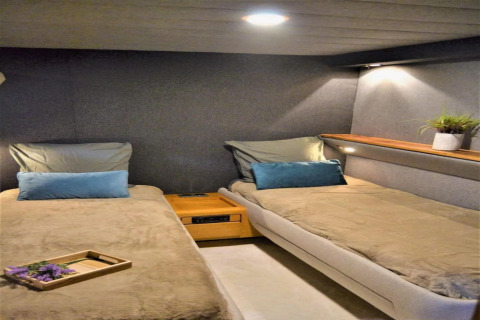 Interior view of Yacht Aquamarina houseboat featuring two single beds, cozy lighting and a potted plant.