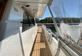 Side walkway on the houseboat Yacht Aquamarina, featuring a wooden deck, railings, and water view.