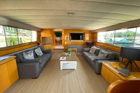 Living room of the houseboat Yacht Aquamarina with large windows, two couches, and a harbor view.