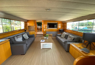Living room of the houseboat Yacht Aquamarina with large windows, two couches, and a harbor view.