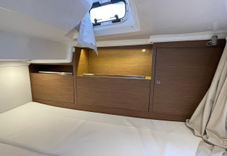 Cozy wood-paneled sleeping area with window on houseboat Yacht Aquamarina, light and modern interior.