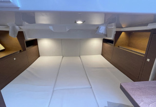 Interior view of a wide sleeping area with wood-panel accents inside the houseboat Yacht Aquamarina.