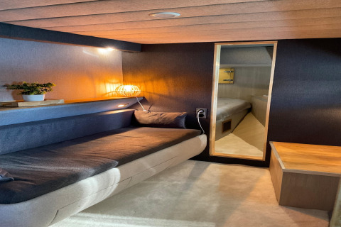 Cozy interior of Yacht Aquamarina houseboat, featuring a sofa, warm lighting, and a bedroom view.