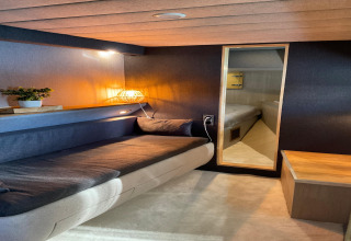 Cozy interior of Yacht Aquamarina houseboat, featuring a sofa, warm lighting, and a bedroom view.