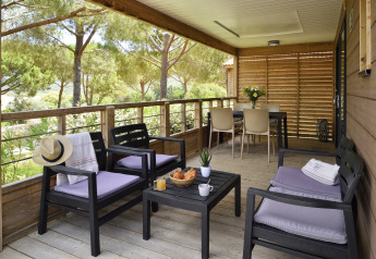 Overdekt terras bij Résidence U Livanti Belvédère Campomoro - Chalet Casane, Frankrijk, met zitje en boszicht.