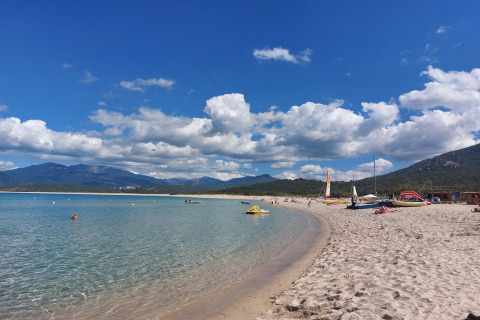 Playa en Résidence U Livanti Belvédère Campomoro, Francia, con agua clara, arena y montañas al fondo.