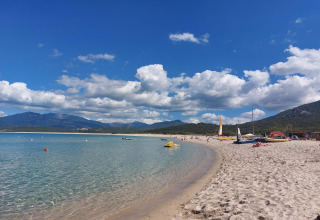 Playa en Résidence U Livanti Belvédère Campomoro, Francia, con agua clara, arena y montañas al fondo.