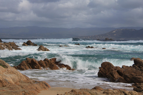 Olas rompen en rocas cerca del chalet Résidence U Livanti Belvédère Campomoro en Francia.