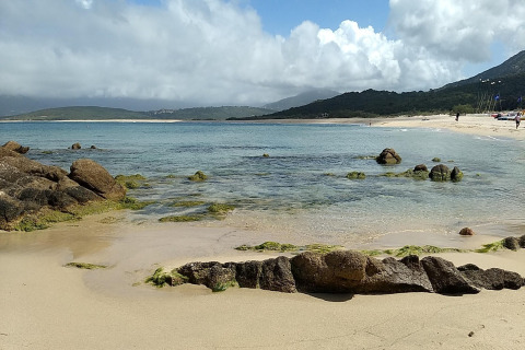 Vista de la playa, rocas y mar en Résidence U Livanti Belvédère Campomoro en Francia en un día con nubes.